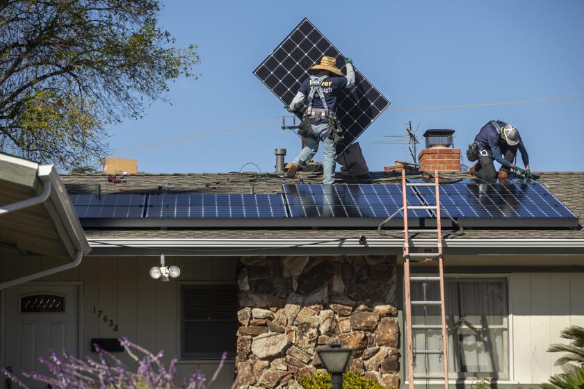 GRANADA HILLS, CA - JANUARY 04, 2020: Tim McKibben, left, a senior installer for the solar company, Sunrun, and installer Aaron Newsom install solar panels on the roof of a home in Granada Hills. (Mel Melcon / Los Angeles Times)