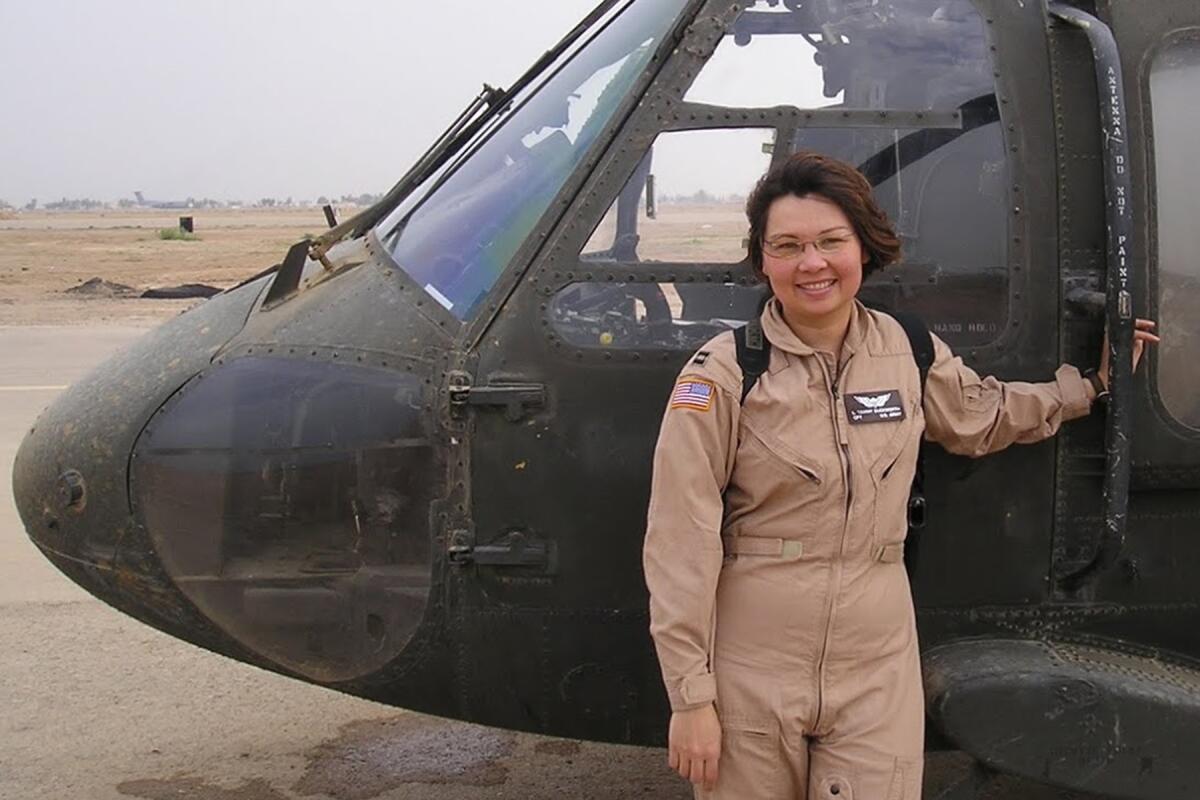 Senator Tammy Duckworth in front of a helicopter.
