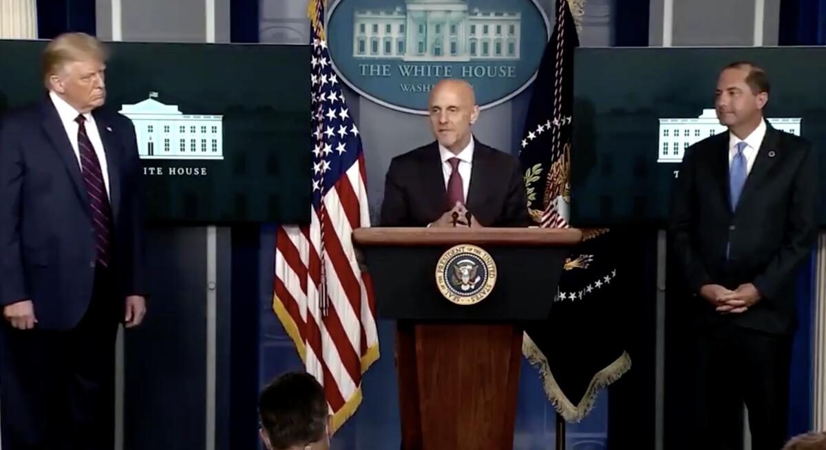 FDA Commissioner Stephen Hahn, flanked by President Trump, left, and HHS Secretary Alex Azar at the White House.