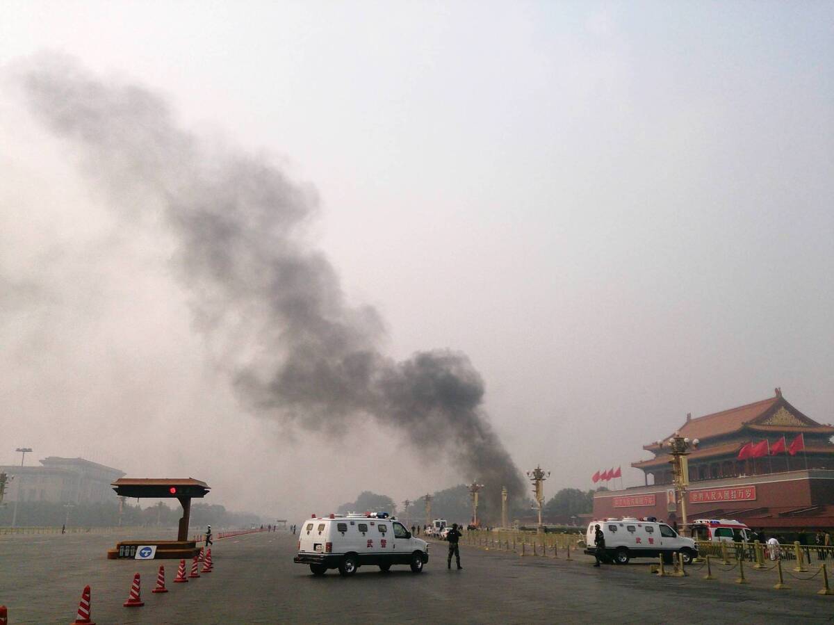 Police block traffic on a street leading into Beijing's Tiananmen Square, where smoke pours from the site where a white SUV crashed after plowing through the crowd.