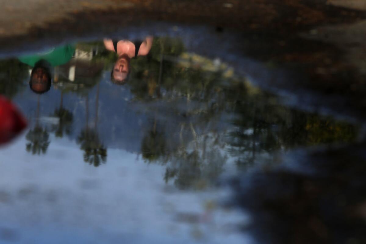 Runners are reflected in a puddle along West Washington Boulevard on a path that rests alongside the Brookside Golf & Country Club in Pasadena.