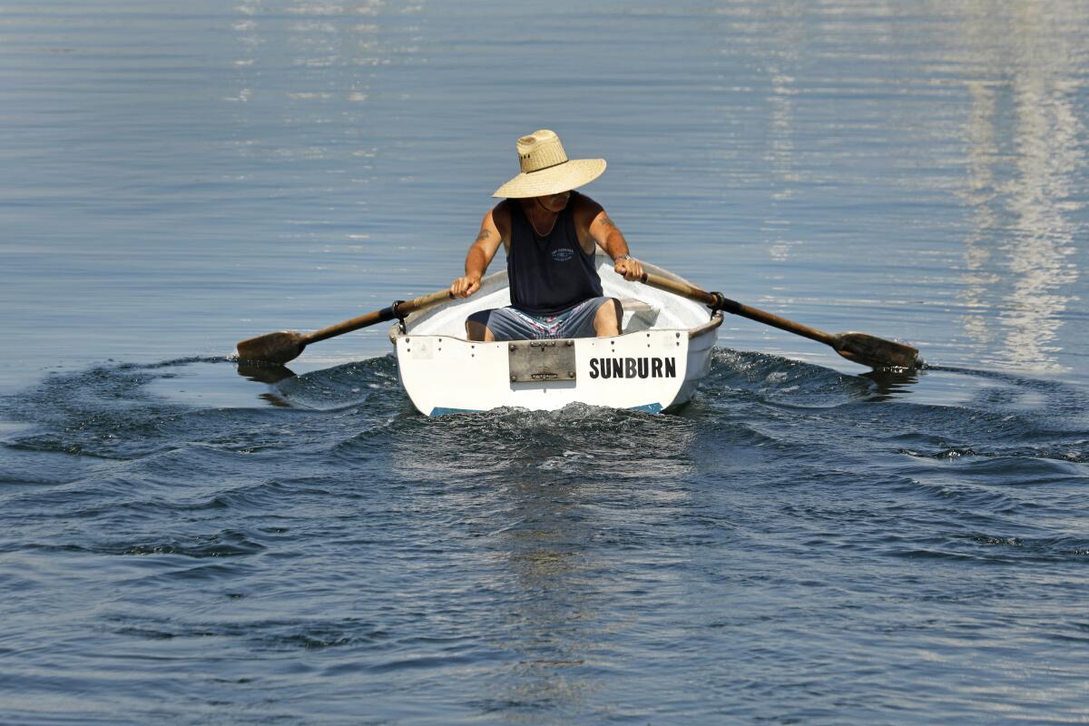 A man in a boat paddles in the marina
