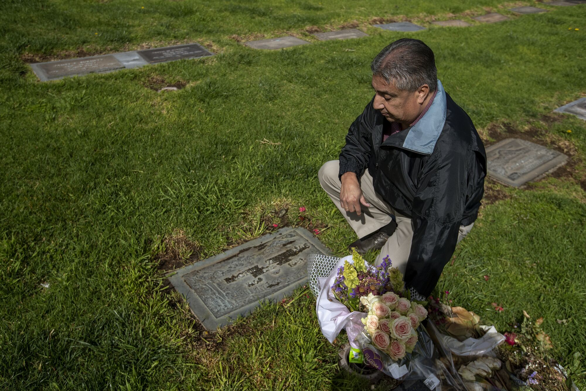 Roy Rodriguez, brother of Rachel Zendejas, kneels next to her grave.
