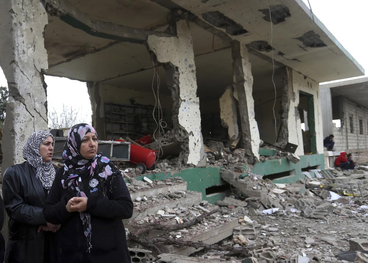Lebanese women gather in front of damaged shops at the site of a deadly car bombing in the town of Nabi Othman in northeast Lebanon.