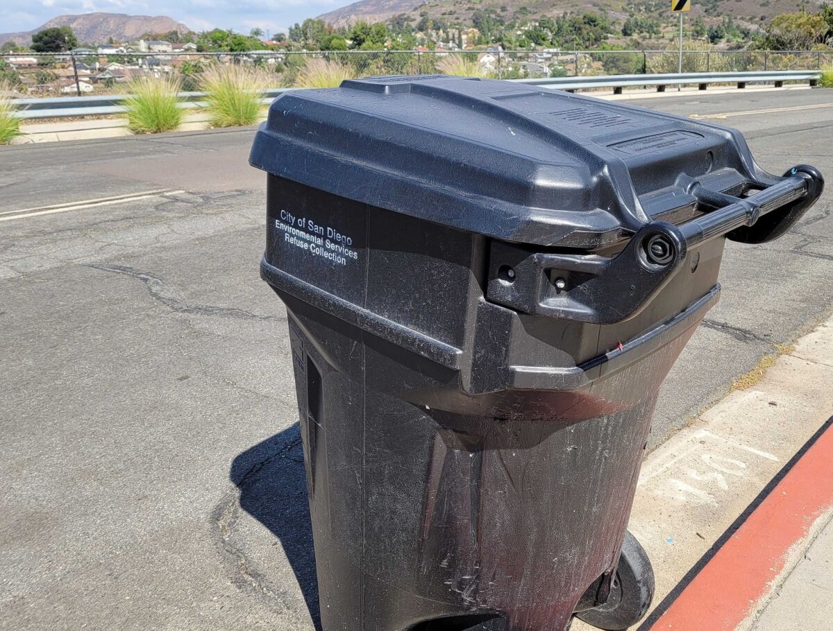 A City of San Diego trash can awaits pickup on a city street.