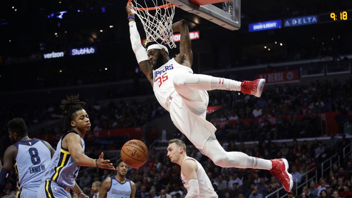 The Clippers' Willie Reed hangs from the rim after dunking against the Memphis Grizzlies on Jan. 2.