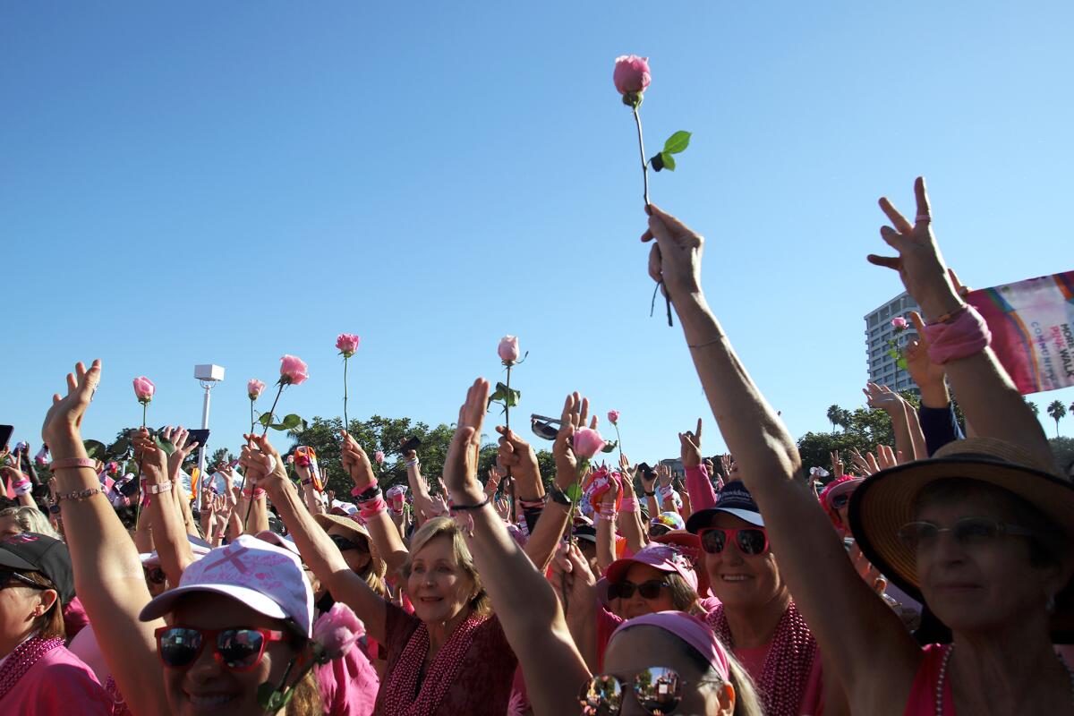 Cancer survivors raise pink roses.