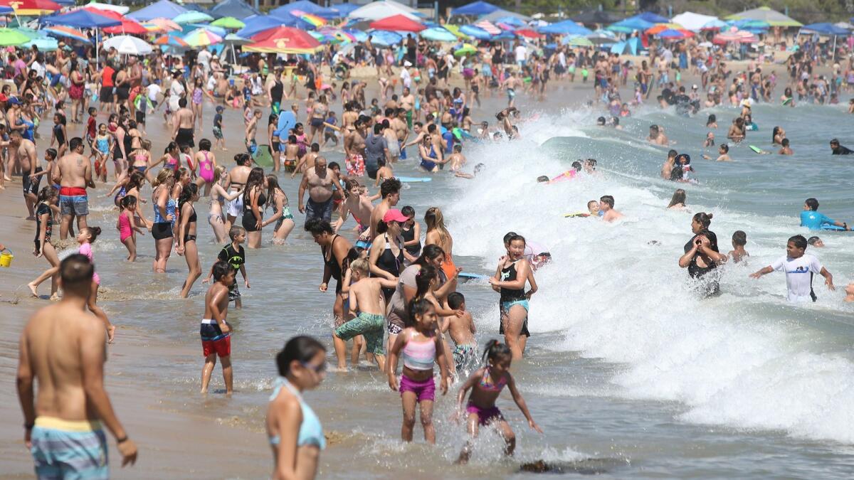People flocked by the thousands to Corona del Mar State Beach in Newport Beach to beat Friday’s heat, which broke the Newport record for July 6.
