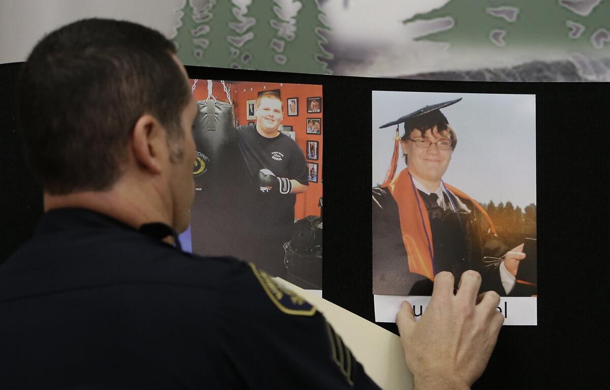 Portland Police Sgt. Pete Simpson places a photo of shooting victim Lucas Eibel, 18, next to a photo of victim Quinn Cooper, 18, during a news conference, Friday, Oct. 2, 2015, in Roseburg, Ore. Cooper, and Eibel, were among those killed when a gunman, Chris Harper-Mercer, walked into a classroom at the Umpqua Community College the day before and opened fire.