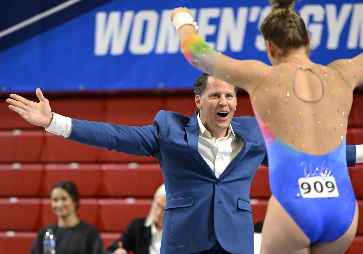 UCLA's Ana Padurariu celebrates with coach Chris Waller after competing on the uneven bars at the 2022 NCAA championships.