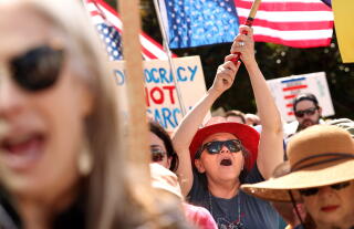 People participate in a peaceful march and rally while holding upside down flags and signs.