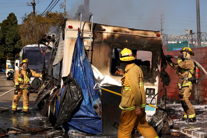 LOS ANGELES, CA - DECEMBER 21, 2022 - - Firefighters put out a fire on an RV, owned by a homeless man, along 2000 S. Granville Ave. in West Los Angeles on December 21, 2022. There are several people that live homeless in their RV's, background, along this street. This is the second day of Los Angeles Mayor Karen Bass' "Safe Inside," program to house the homeless of Los Angeles. (Genaro Molina / Los Angeles Times)