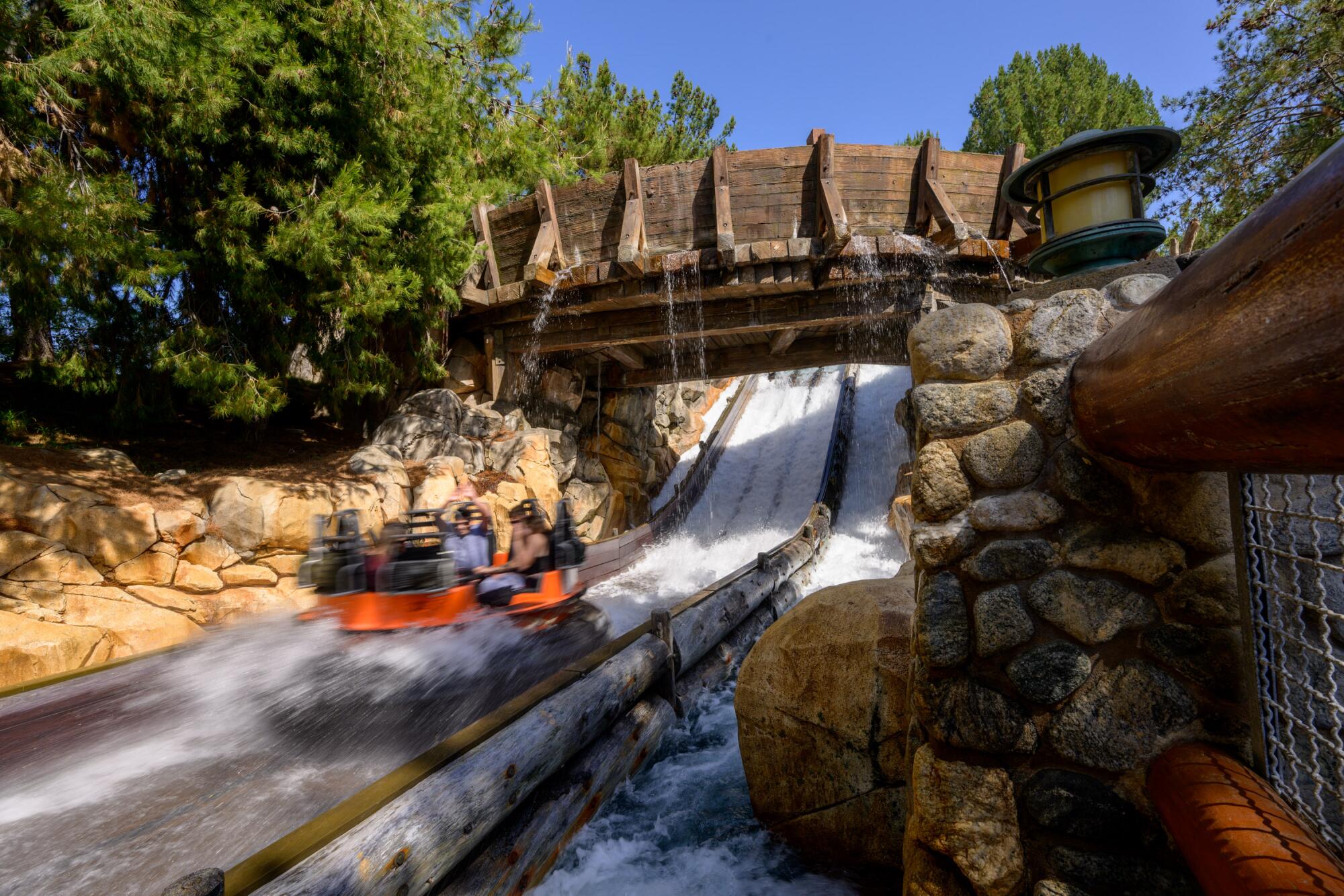 People on a raft in a California Adventure water ride bumping against a rock with rapid waters all around them