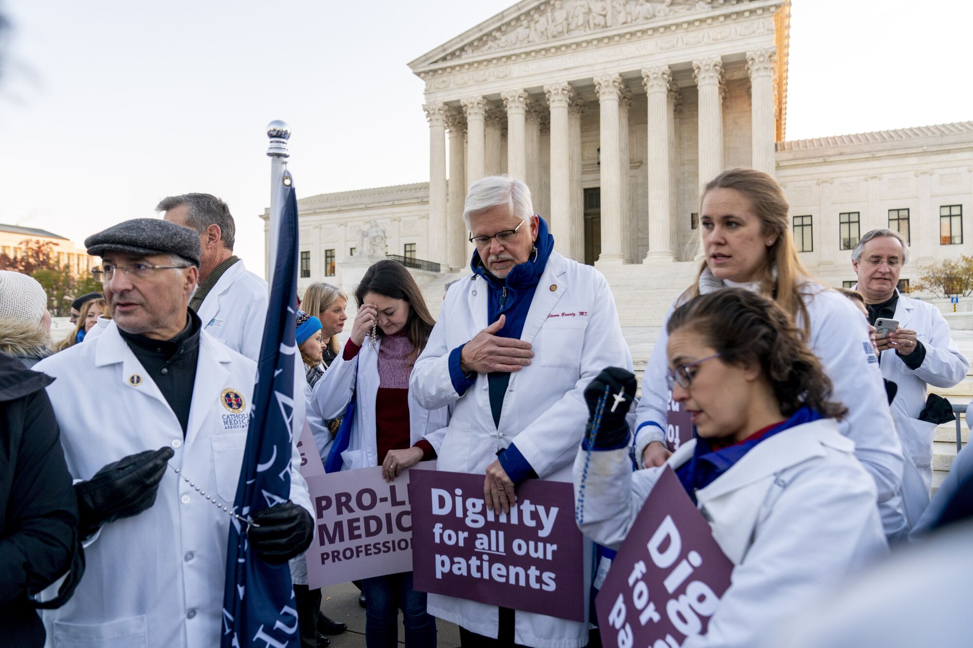 Anti-abortion protesters wearing doctor uniforms pray in front of the U.S. Supreme Court.
