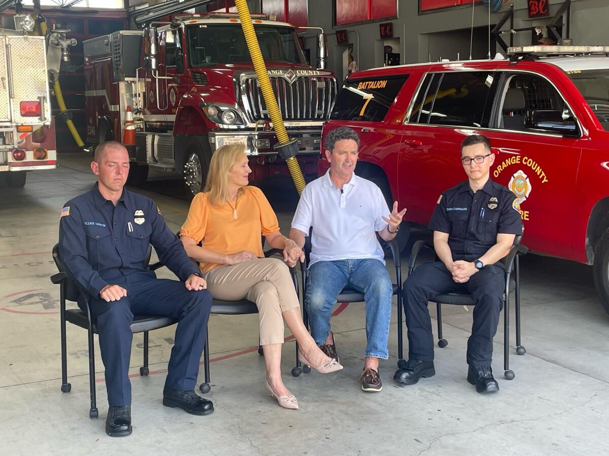 Four people sit on chairs at a fire station.