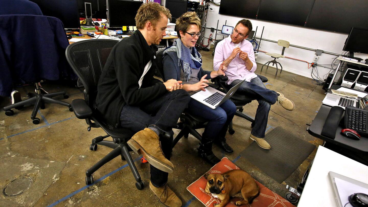 Brennan Roberts, left, Kate Hollenbach, center, and Alan Brown, right, collaborate as Laika the dog sits nearby during a tour of Oblong in downtown Los Angeles. The business is housed in a former railroad depot.