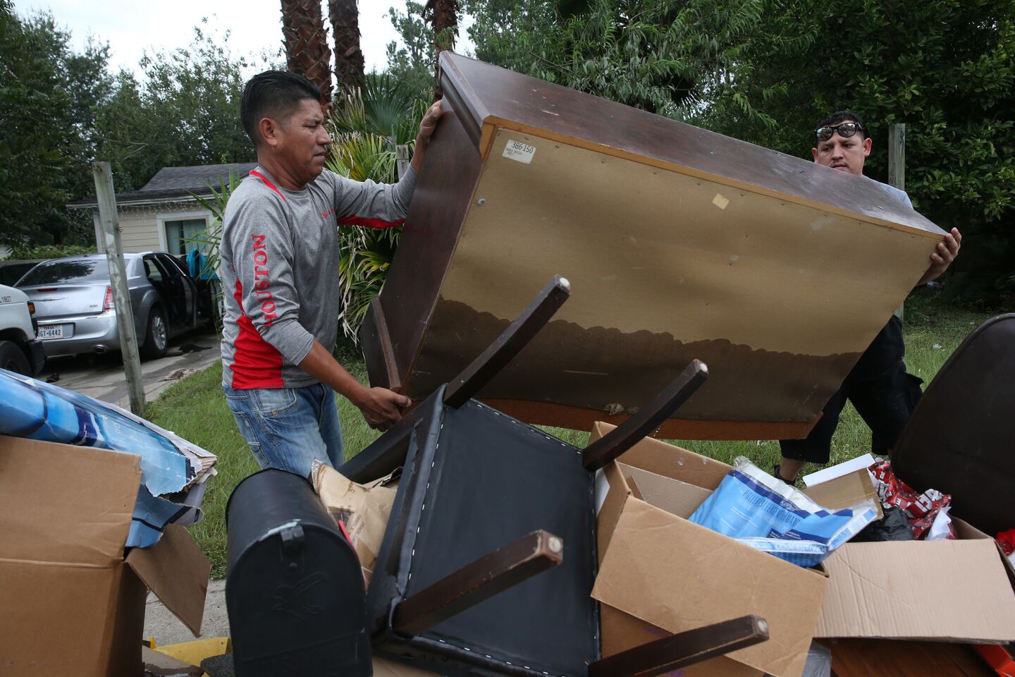 Rafael Minor, left, and Miguel Ramirez remove the contents from a flooded home in northeast Houston on Wednesday.