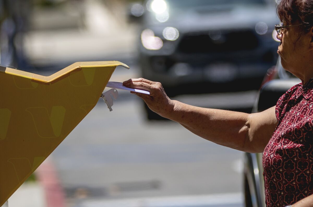 A voter drops her ballot in a box.