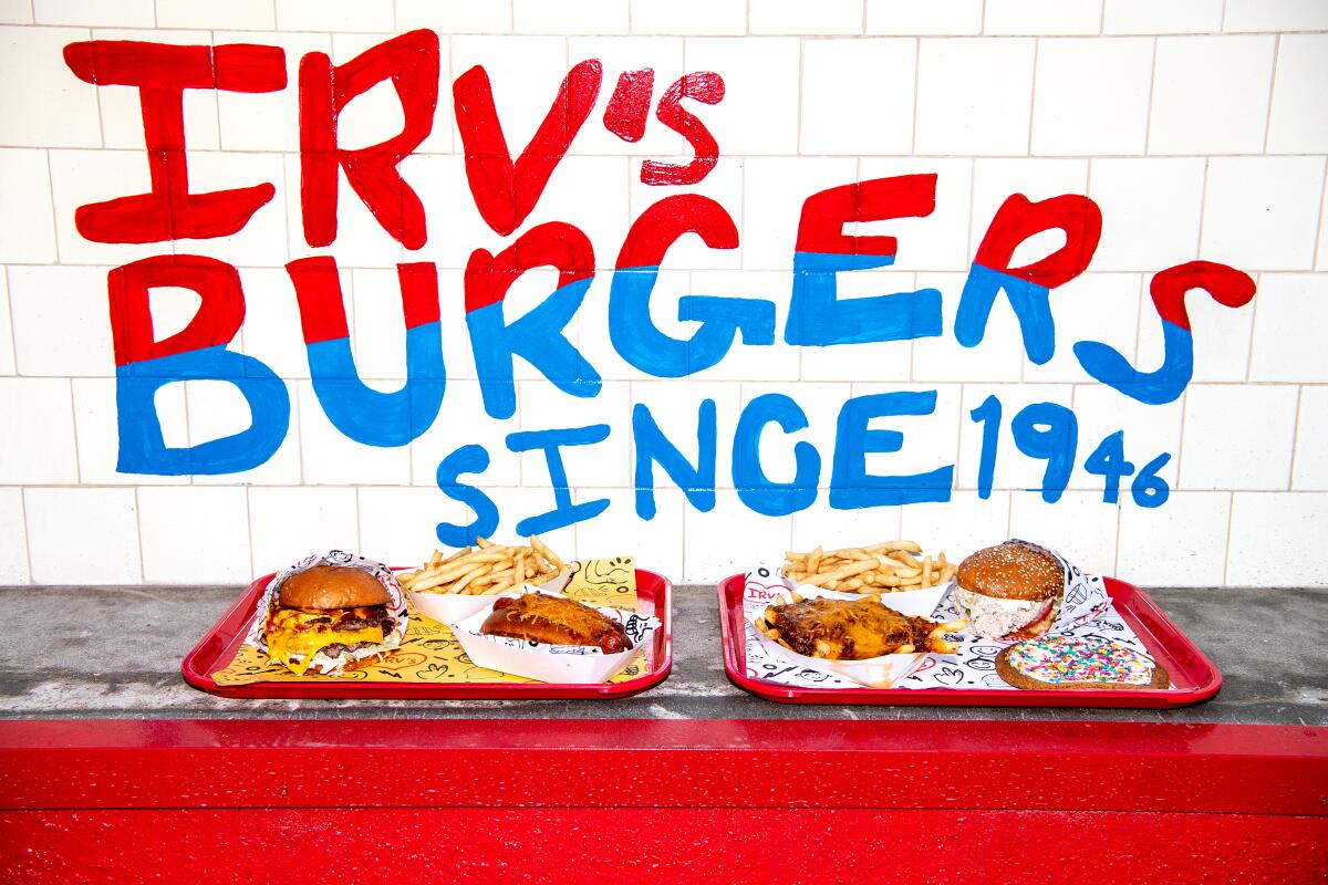 Two trays of burgers and fries in front of a wall that reads "Irv's Burgers since 1946"