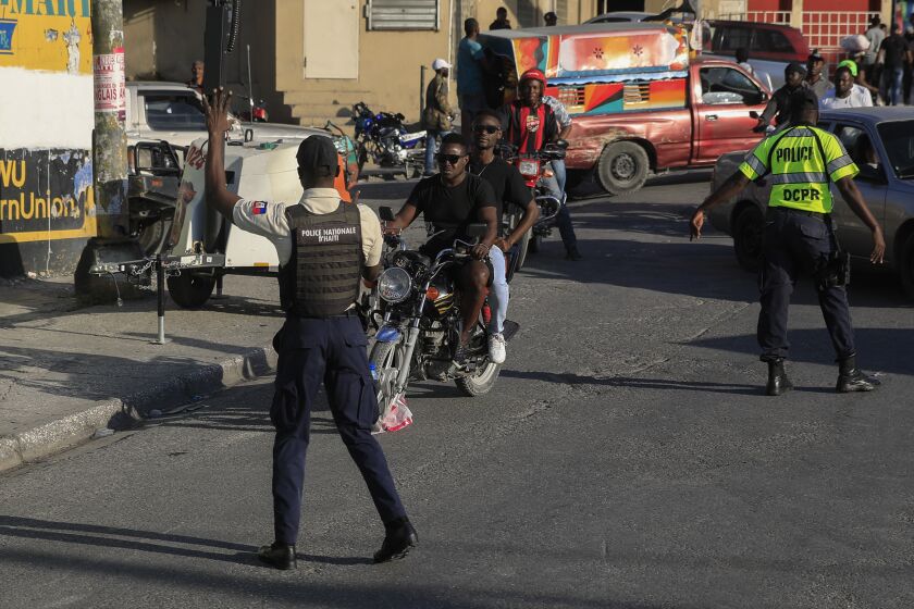National police control security on a street in Port-au-Prince, Haiti, Saturday, Jan. 21, 2023. One of Haiti's gangs stormed a key part of the capital, Port-Au-Prince, and battled with police throughout the day, leaving at least three officers dead and another missing. (AP Photo/Odelyn Joseph)