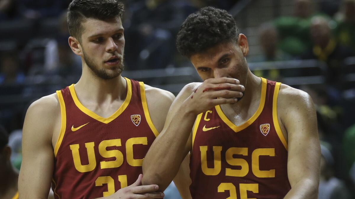 USC's Nick Rakocevic, left, helps teammate Bennie Boatwright off the floor after his nose was bloodied on a play against Oregon in the second half on Sunday.