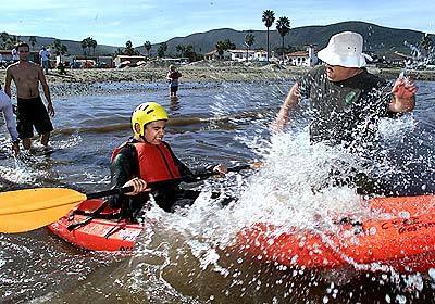 Eric Shaw, director of the Wilderness Education Program, assists Luis Baca, of Mexico, break through a wave on a kayak.