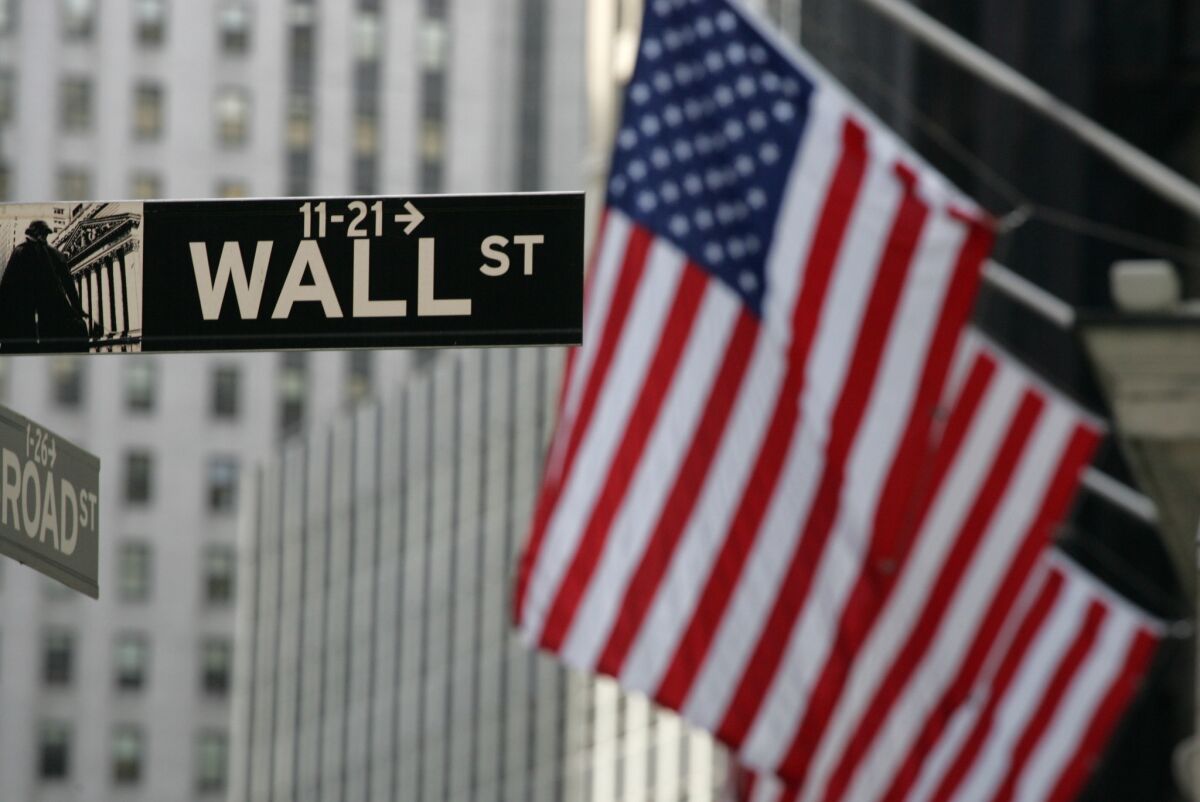 A Wall Street sign next to U.S. flags in New York
