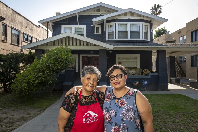 PASADENA, CA-JUNE 30, 2023: Cecilia Turcios, left, and her daughter Desiree Alvarado, are photographed in front of the board and care home that Desiree owns and operates in Pasadena. Turcios is the house manager. Alvarado bought the property in 2008 and she and her family have run it since. Alvarado says It's incredibly hard to stay open given the low reimbursement rates. (Mel Melcon / Los Angeles Times)