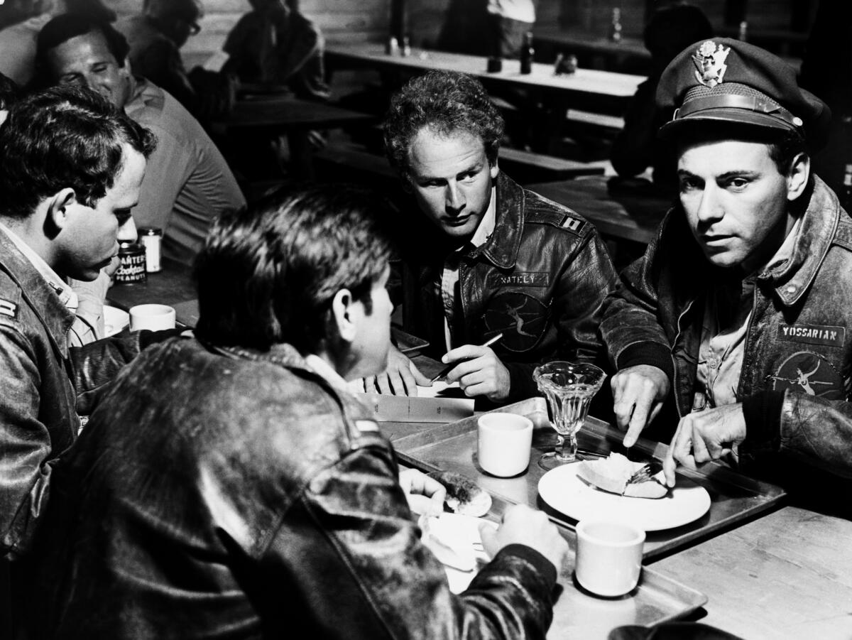 Military men in uniform converse over coffee.