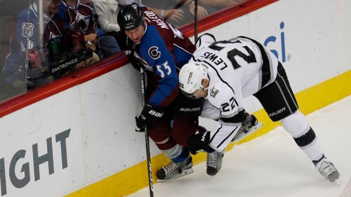 Avalanche forward Cody McLeod is checked into the boards by Kings center Trevor Lewis while chasing the puck during the first period of a game on Nov. 15.