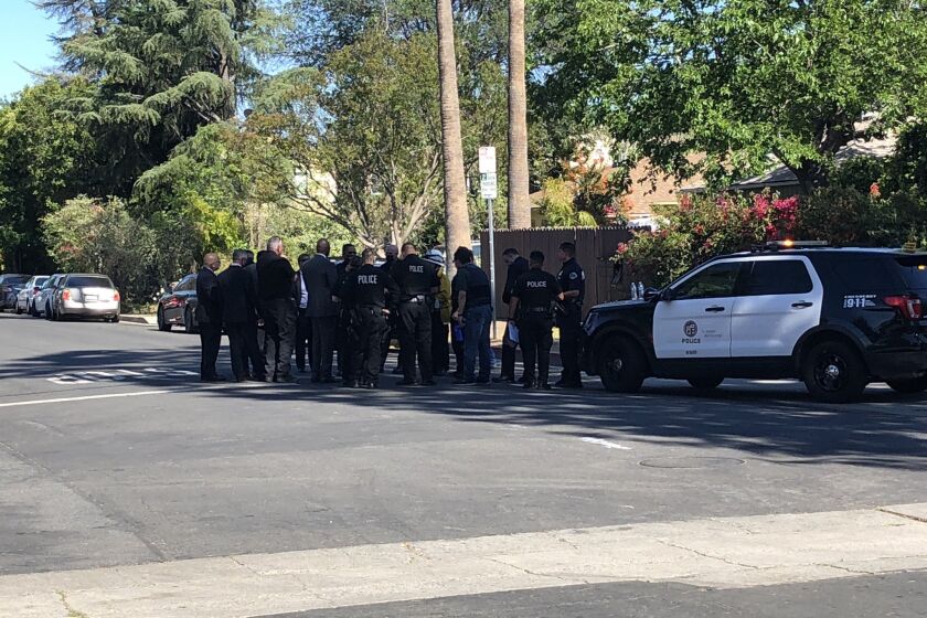 Investigators gather near the scene where an off-duty LAPD officer was shot on Wednesday.