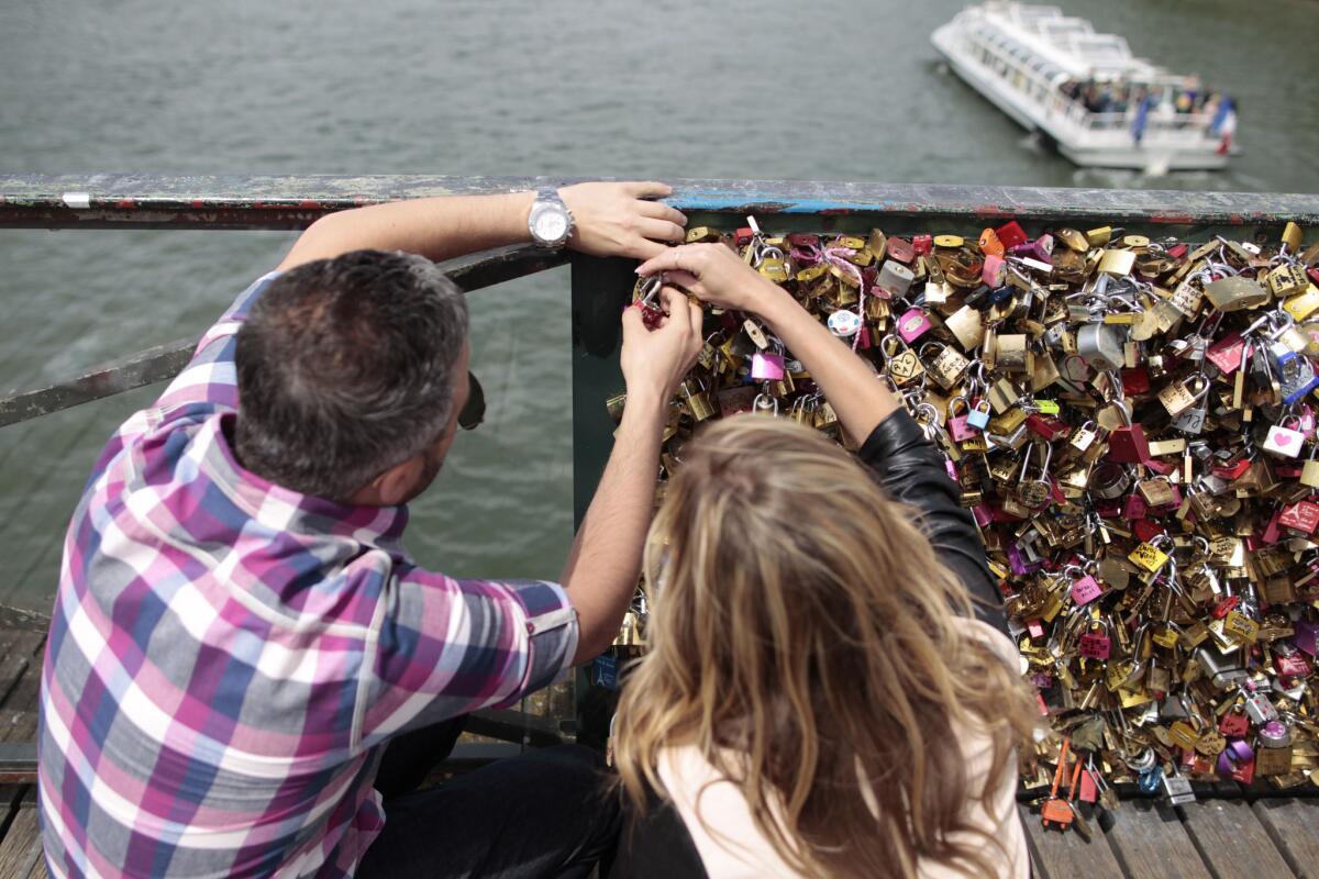 A couple locks a padlock to the Pont des Arts on May 29, 2015, in Paris.