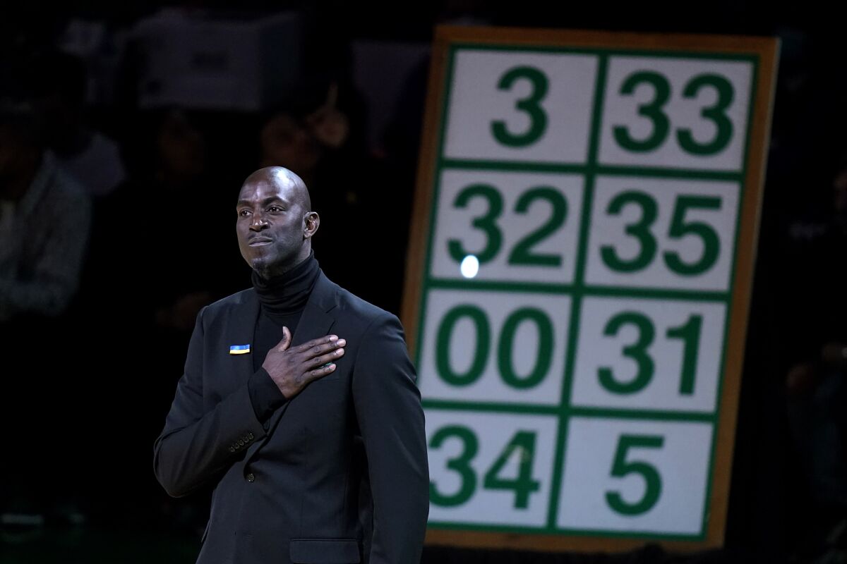 Kevin Garnett, stands in front of a replica of a banner featuring his No. 5 jersey during ceremonies to retire the number to the rafters following an NBA basketball game between the Dallas Mavericks and the Boston Celtics in Boston, Sunday, March 13, 2022. (AP Photo/Steven Senne)