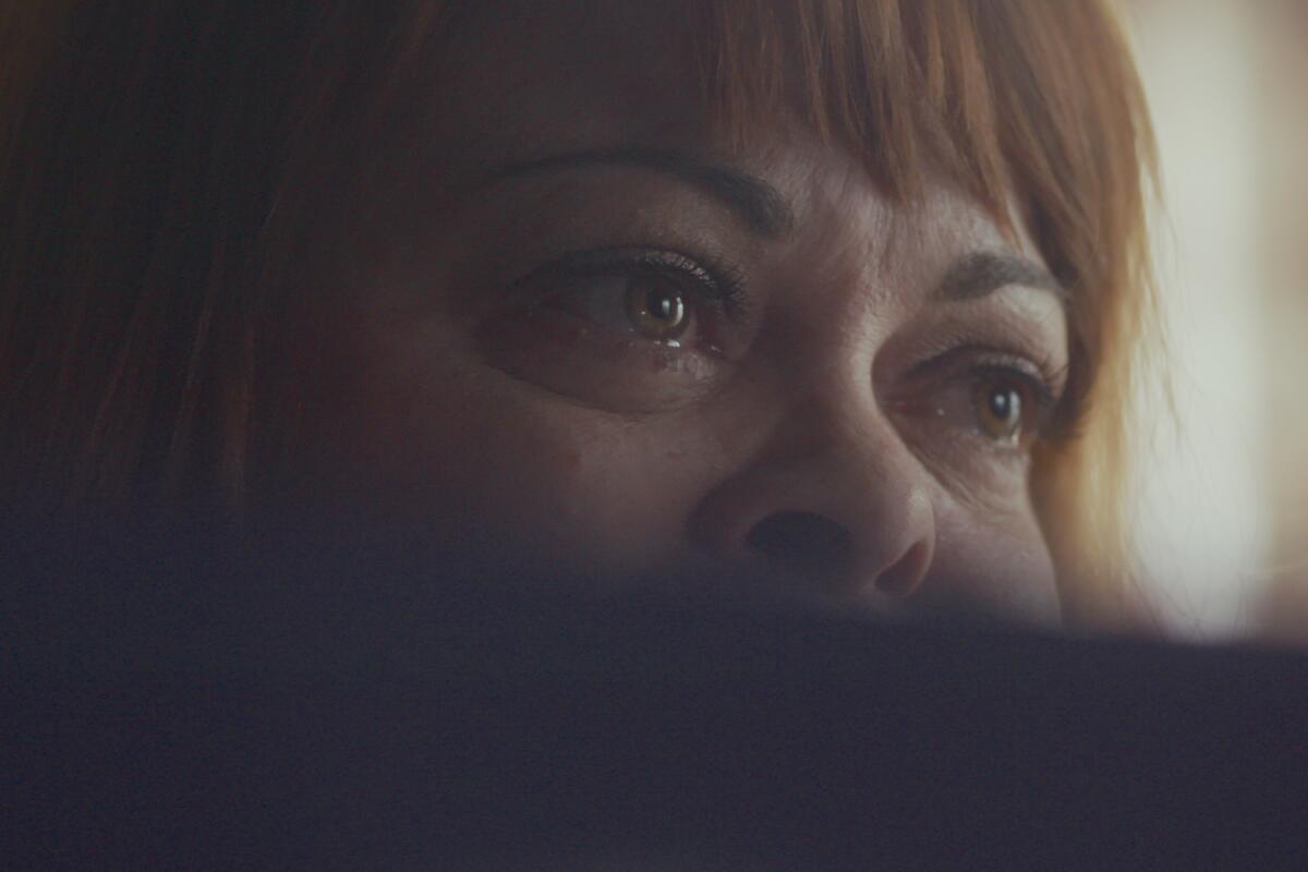 A close-up image of a woman's face over her computer screen