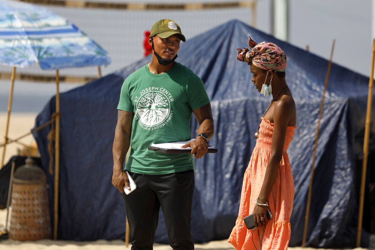 Two people speak in front of a tent