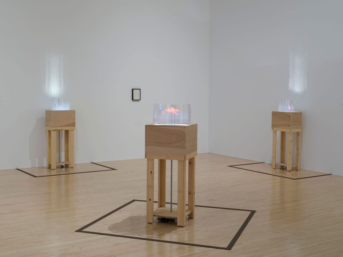 three projectors on wooden stands in an art installation