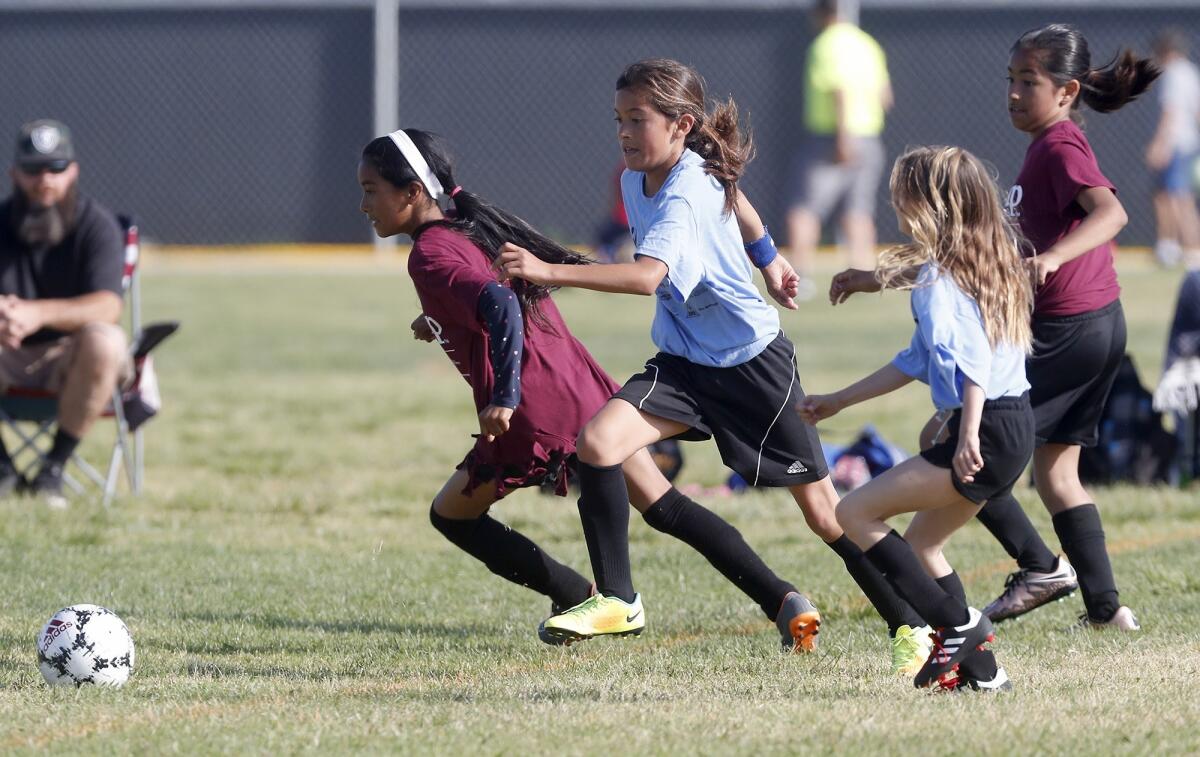 California Elementary's Sophia Zarate, center, chases down a loose ball against Sonora in a girls’ third- and fourth-grade Bronze Division pool-play match at the Daily Pilot Cup on Thursday at Costa Mesa High.