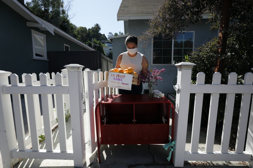 Vreny Palacios sets out a box of oranges to share in front of her home. 