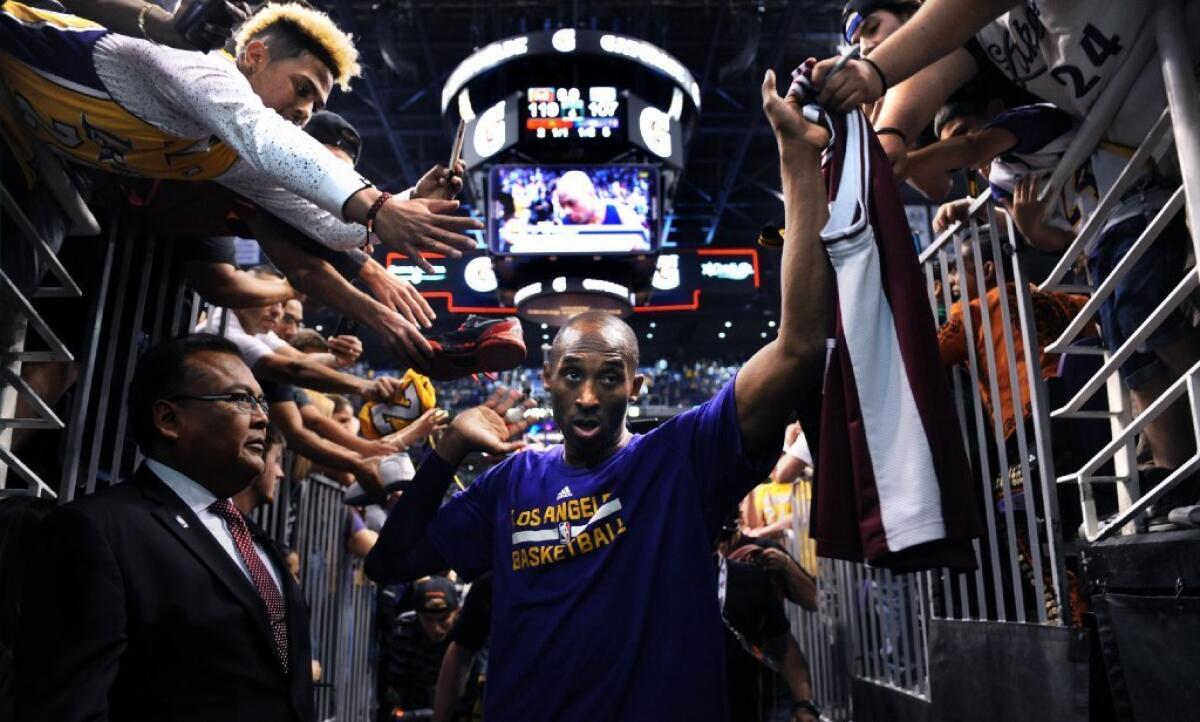 Kobe Bryant high-fives fans as he walks off the court for the last time in Phoenix after a game against the Suns on March 23.