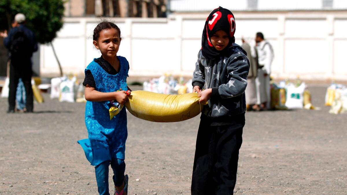 Children carry food aid distributed by a charity in Sana on June 7. Nearly a quarter of Yemen’s population is “one step away from famine,” the U.N. humanitarian chief says.