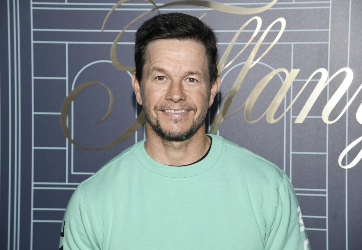 Mark Wahlberg wears a light green long-sleeved shirt as he poses for photos