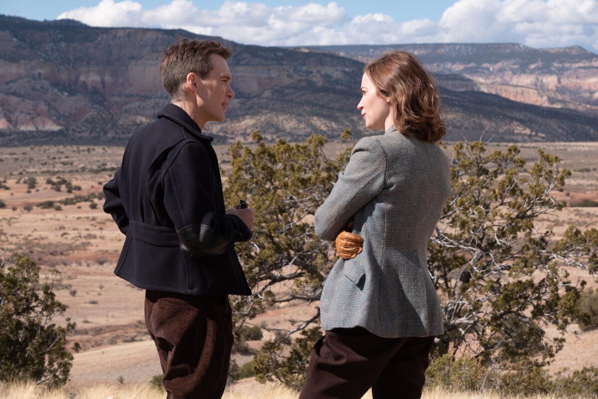A man and a woman in '40s clothes talk before a New Mexico desert landscape in "Oppenheimer."