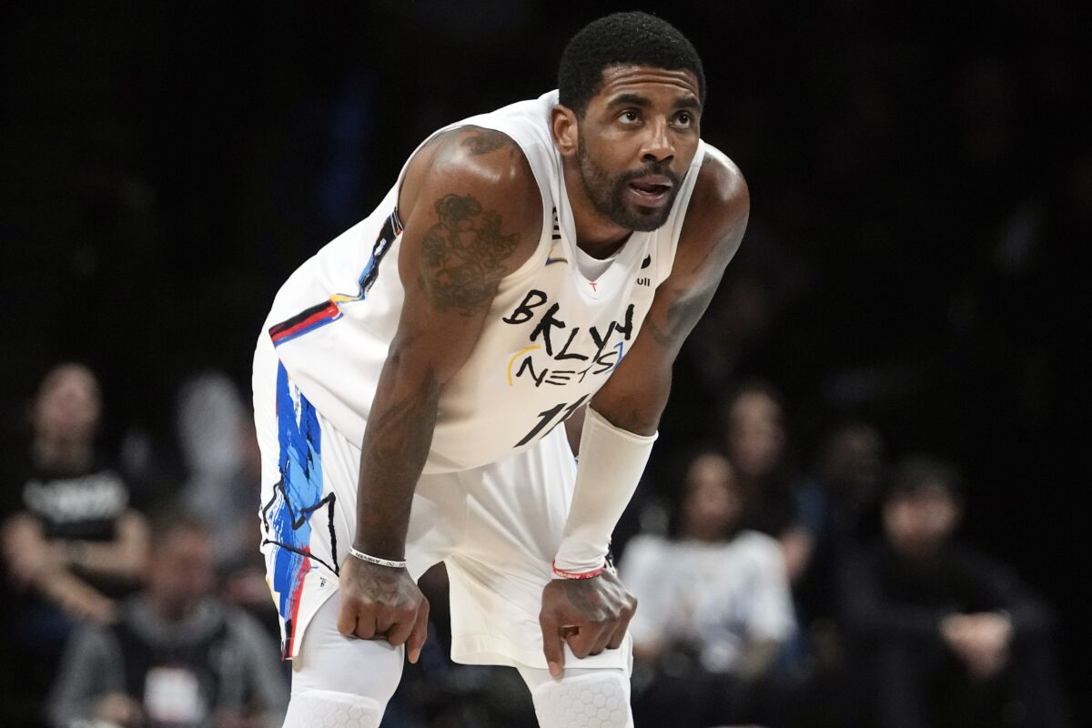 Nets guard Kyrie Irving bends over to catch his breath during a break in play.