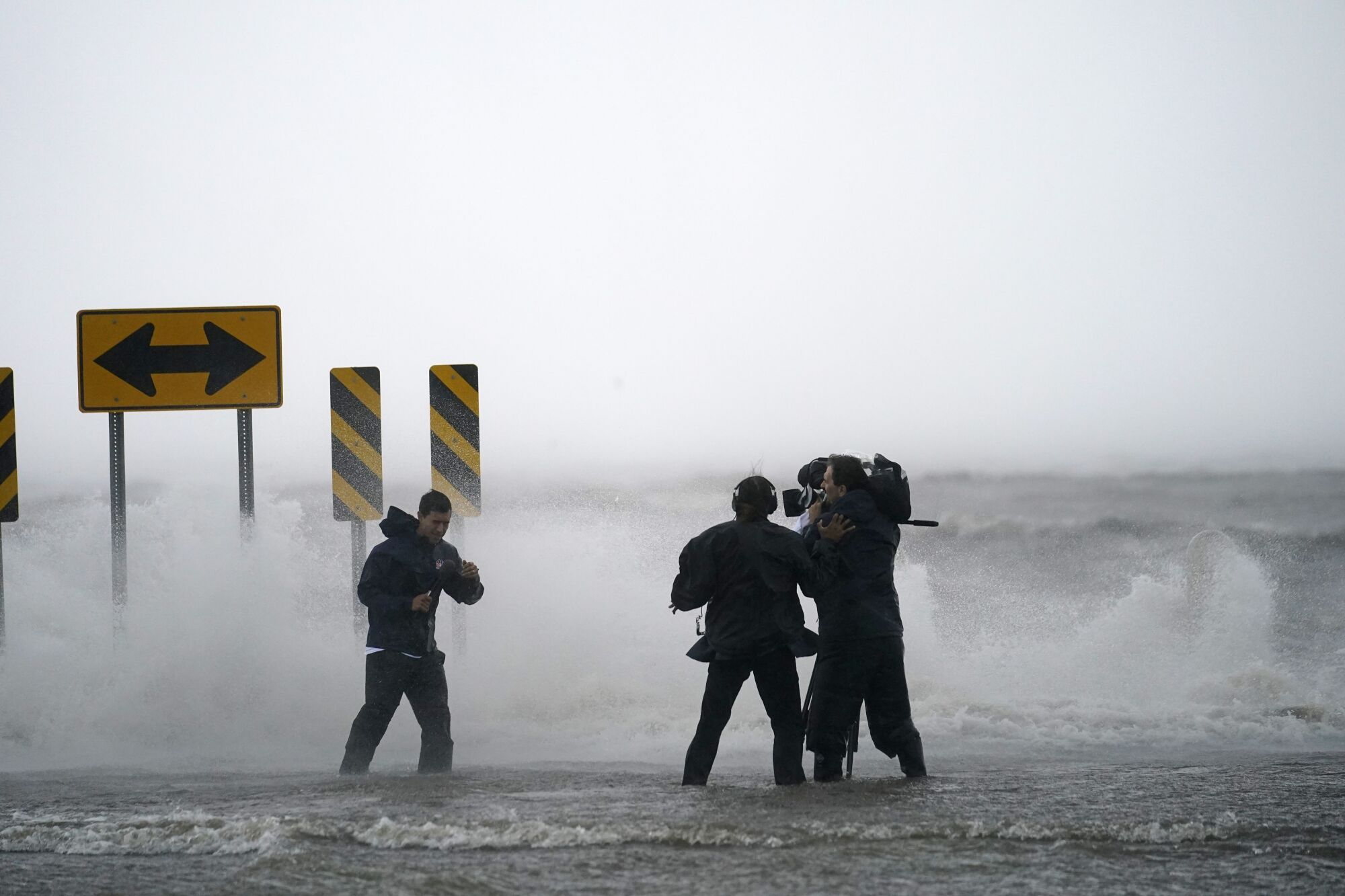 A camera crew films a reporter in rain and high water.
