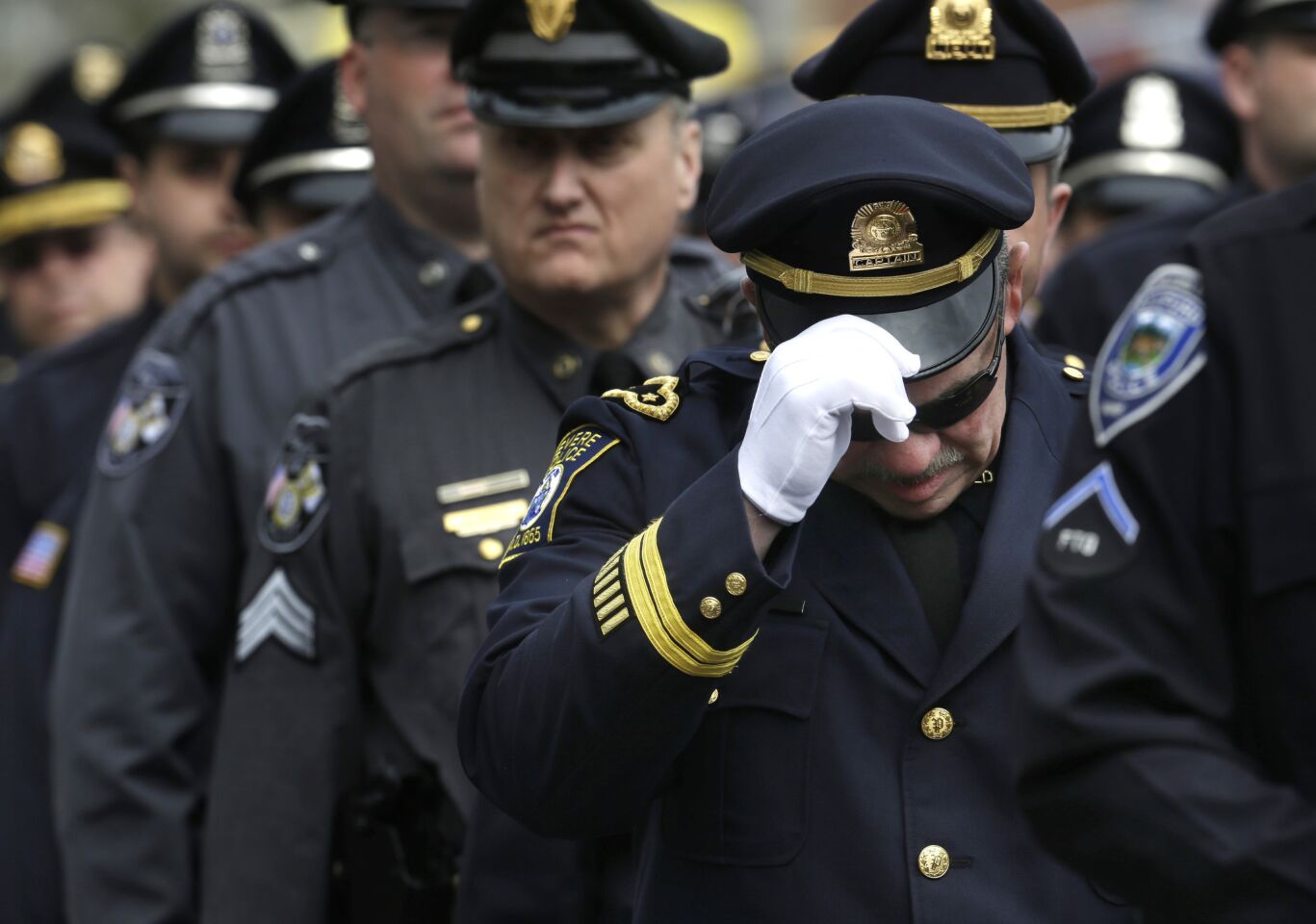 A Revere, Mass. police captain holds his cap while entering a memorial service for fallen MIT police officer Sean Collier, in Cambridge, Mass.