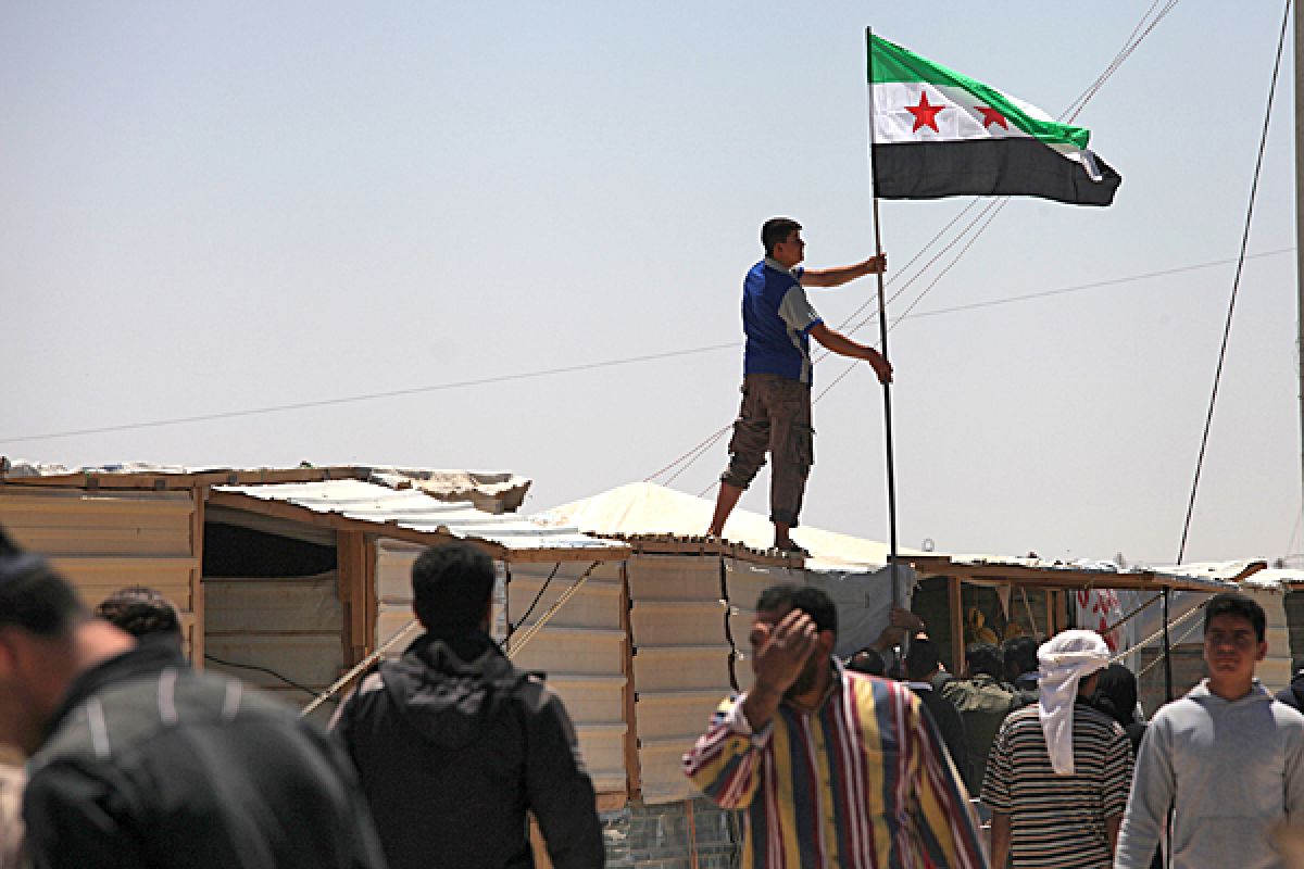A Syrian refugee hoists the Syrian revolutionary flag over a makeshift shop, during a strike at Zaatari refugee camp, in Mafraq, Jordan.