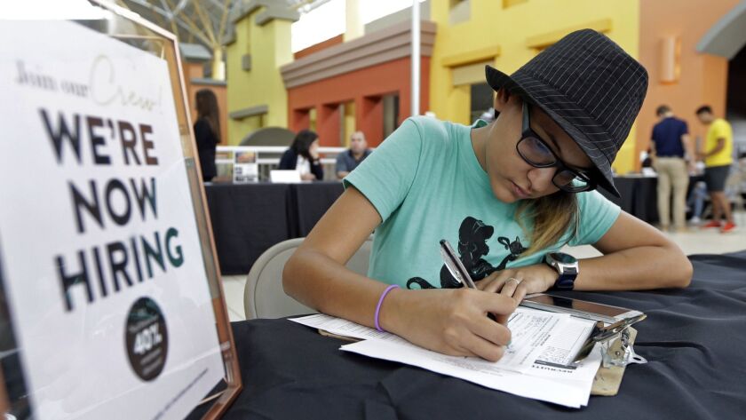 Alejandra Bastidas fills out an application at a job fair at Dolphin Mall in Sweetwater, Fla., in October 2017.