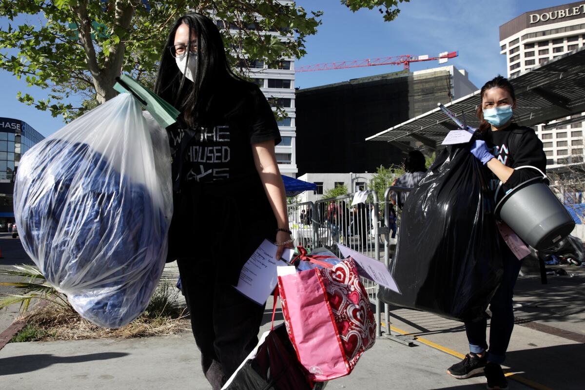 Masked volunteers carrying bags and other belongings