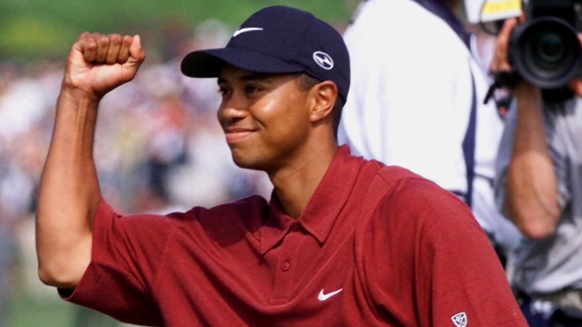 Tiger Woods celebrates by holding up a fist and smiling.
