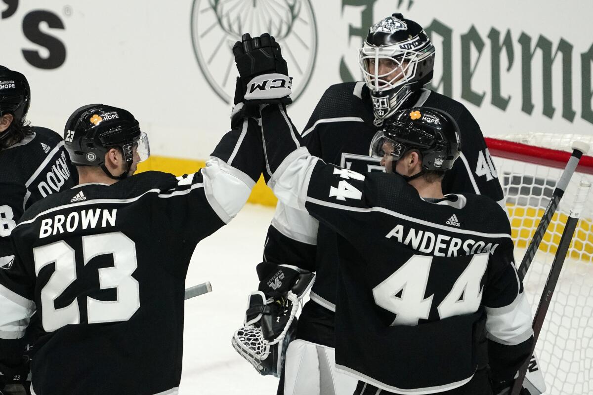 Kings right wing Dustin Brown and defenseman Mikey Anderson celebrate in front of goaltender Calvin Petersen.